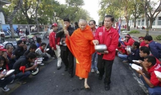 Mnich kropí svatou vodou demonstranty u parlamentu.