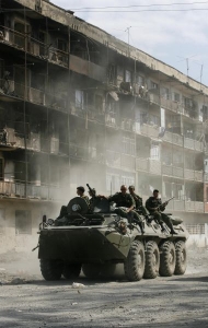 Ruský obrněný transportér projíždí zničeným městem Cchinvali.
