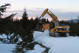 Těžká technika nabírá sníh v Jizerských horách a odváží jej do Vesce.
