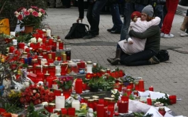 Lidé nosí k místu masakru květiny a svíčky.
