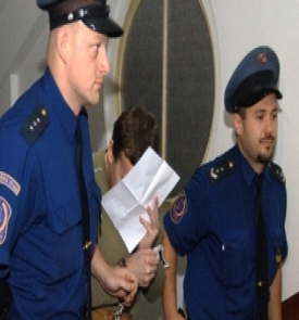 Petra Zelenku vede vězeňská eskorta.