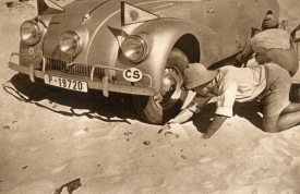 Hanzelka a Zikmund se snaží vyhrabat svůj vůz z písku poblíž rovníku.