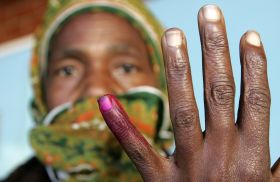 Žena s prstem označeným inkoustem opouští volební místnost.