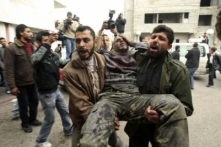 Palestinci odnášejí zraněného muže do bezpečí.